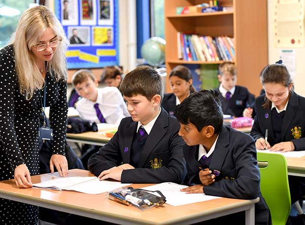 Eine Lehrerin unterstützt zwei internationale Schüler der LVS Ascot im Klassenzimmer, während andere Schüler konzentriert arbeiten.